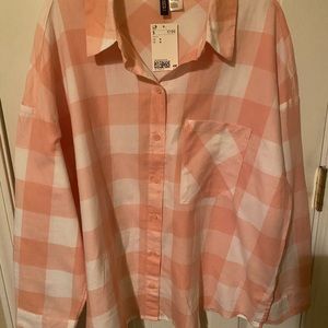 A peach colored wide shouldered plaid shirt, still new with a tag